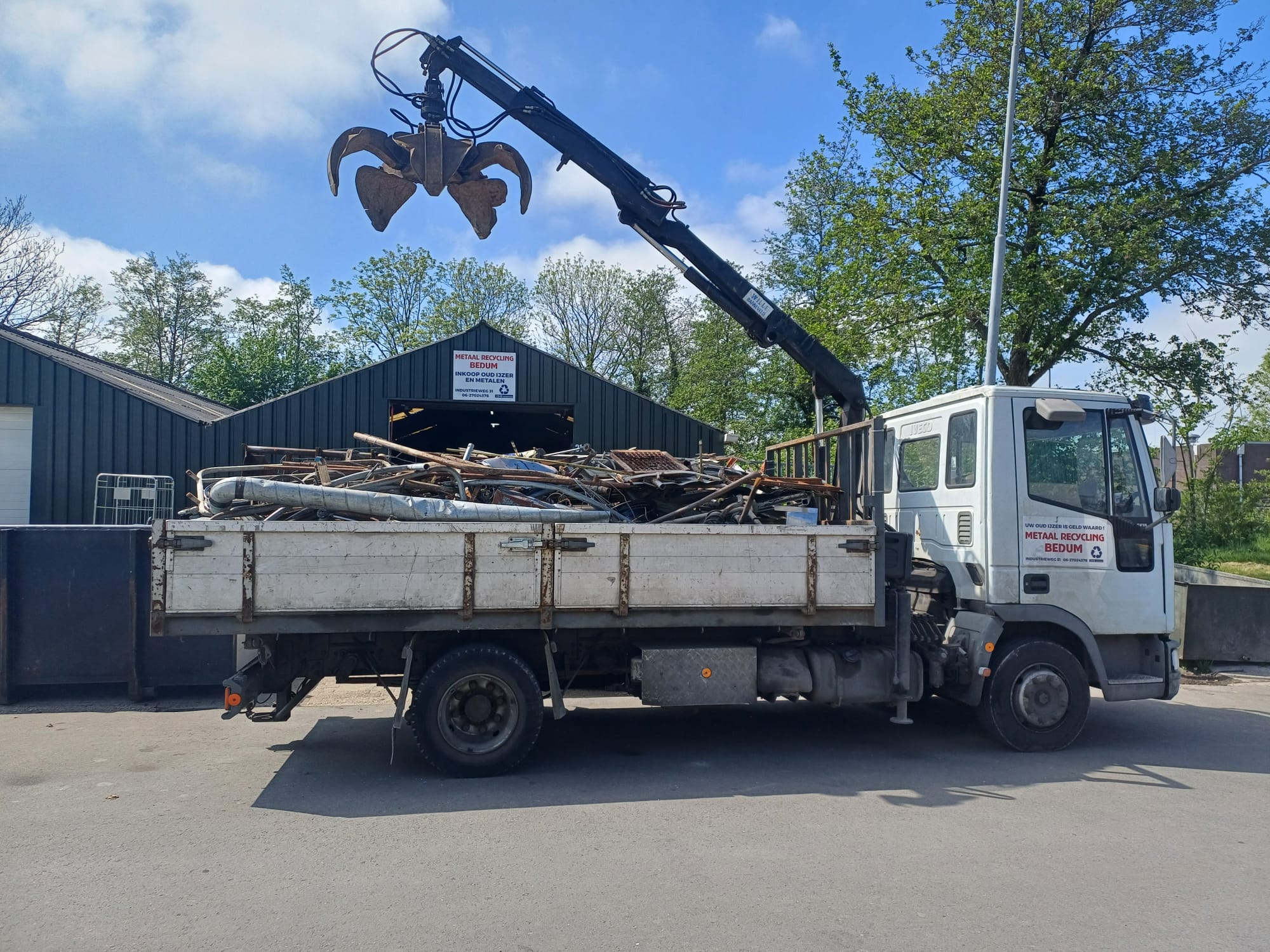 De standplaats van Metaal Recycling Bedum met een truck in de voorgrond met vele soorten metaal, koper en ijzer erin.